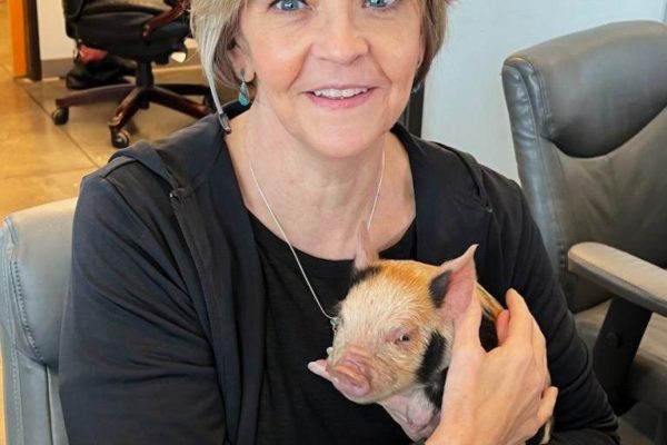 Office Manager Andrea with a baby piglet